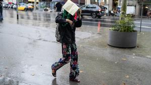Una chica se protege con una revista de la lluvia, el pasado día 1, en el centro de Barcelona.