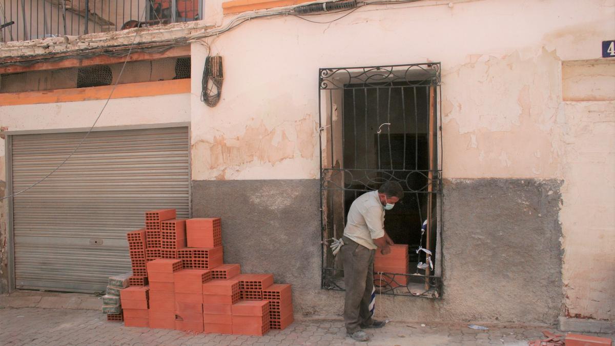 Un obrero tapia una de las ventanas de la vivienda, este viernes.