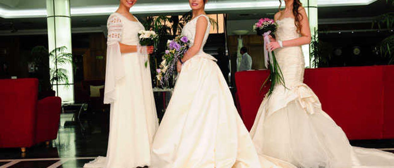 Tres jóvenes muestran tres trajes de novias durante la Primera Muestra Bodas 2015 del Elba Vecindario.