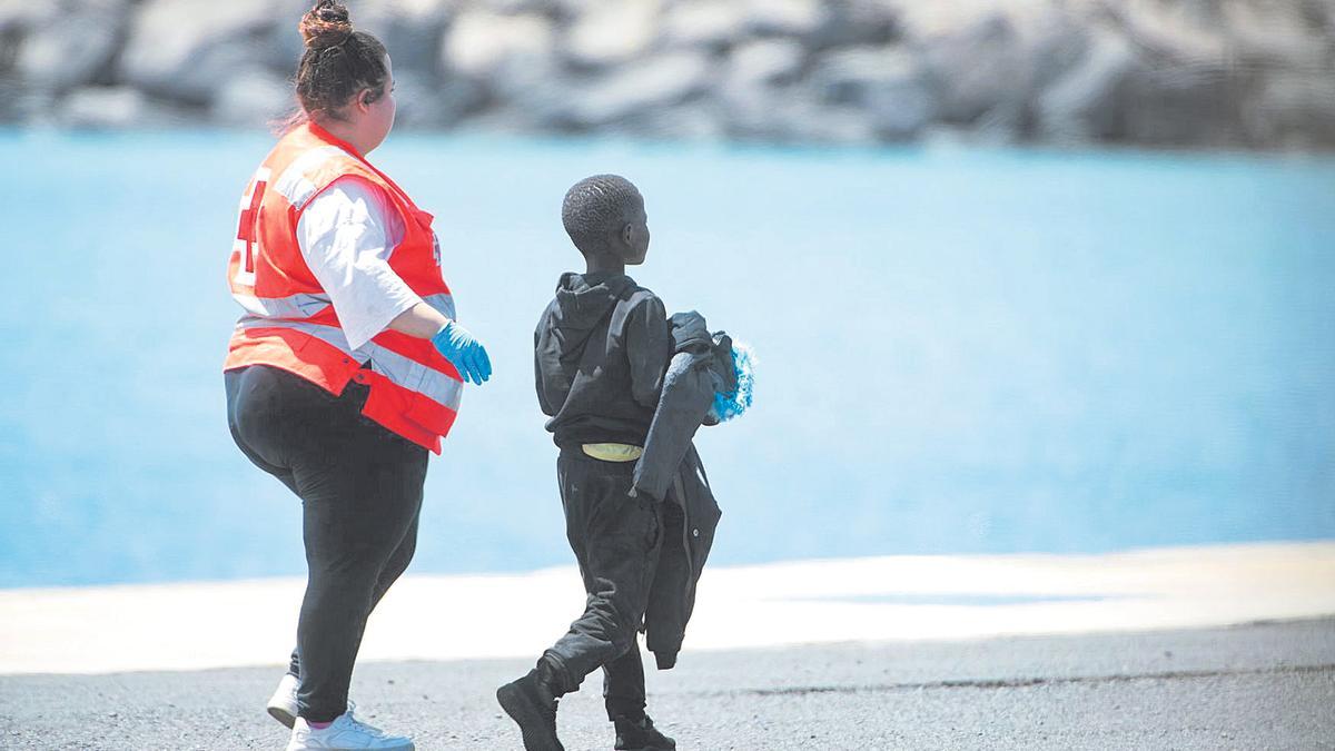 Un menor migrante junto a una voluntaria de Cruz Roja en el muelle de Puerto del Rosario, en Fuertevenura.