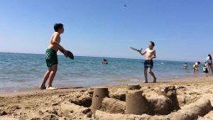 Dos niños juegan a las palas junto a un castillo de anera en la playa de Gavà,