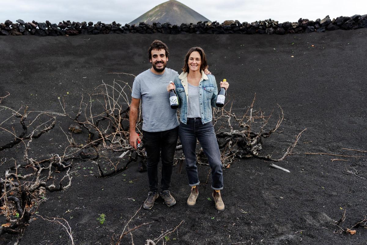 Daniel Ramírez y Marta Labanda en una de sus parcelas con dos botellas de su vino en Lanzarote.