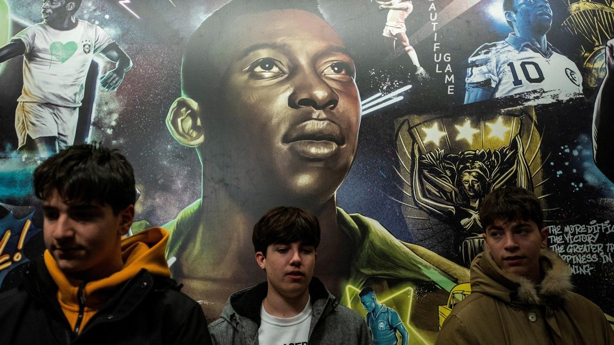 Unos jóvenes posan junto a un mural por la muerte de Pelé.