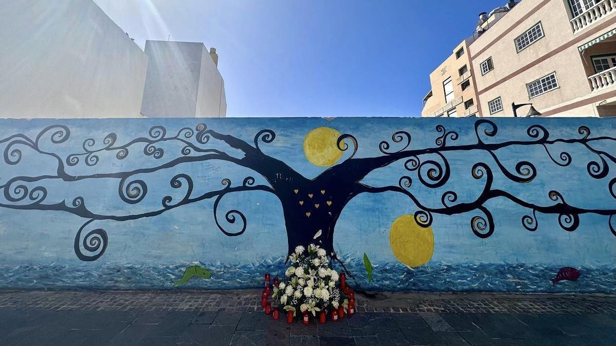 Imagen del mural con las velas y flores en el lugar del derrumbe.