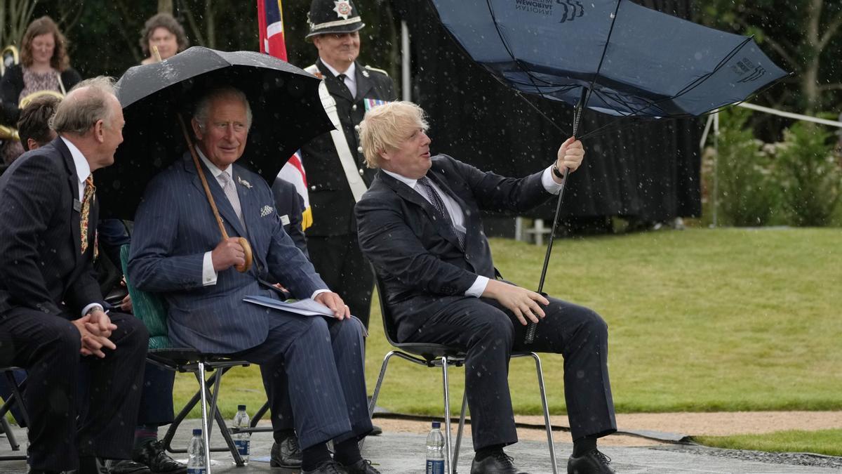 Boris Johnson trata de controlar el paraguas durante un acto oficial.