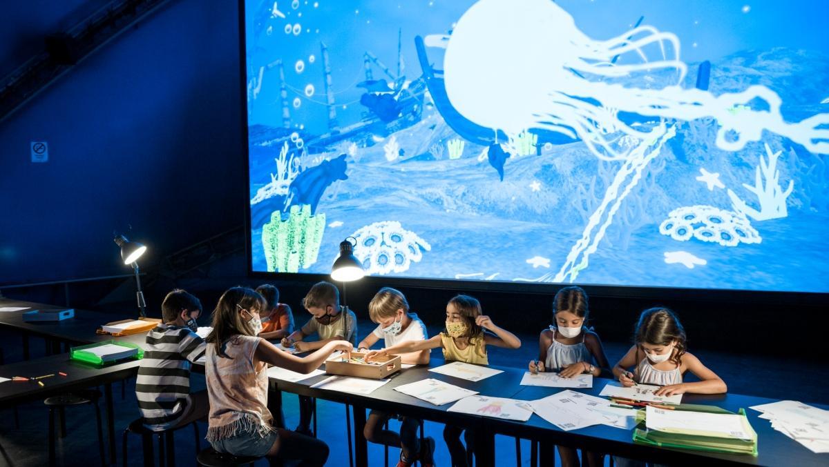 Unos niños pintan sus dibujos para luego hacerlos reales en el acuario gigante.