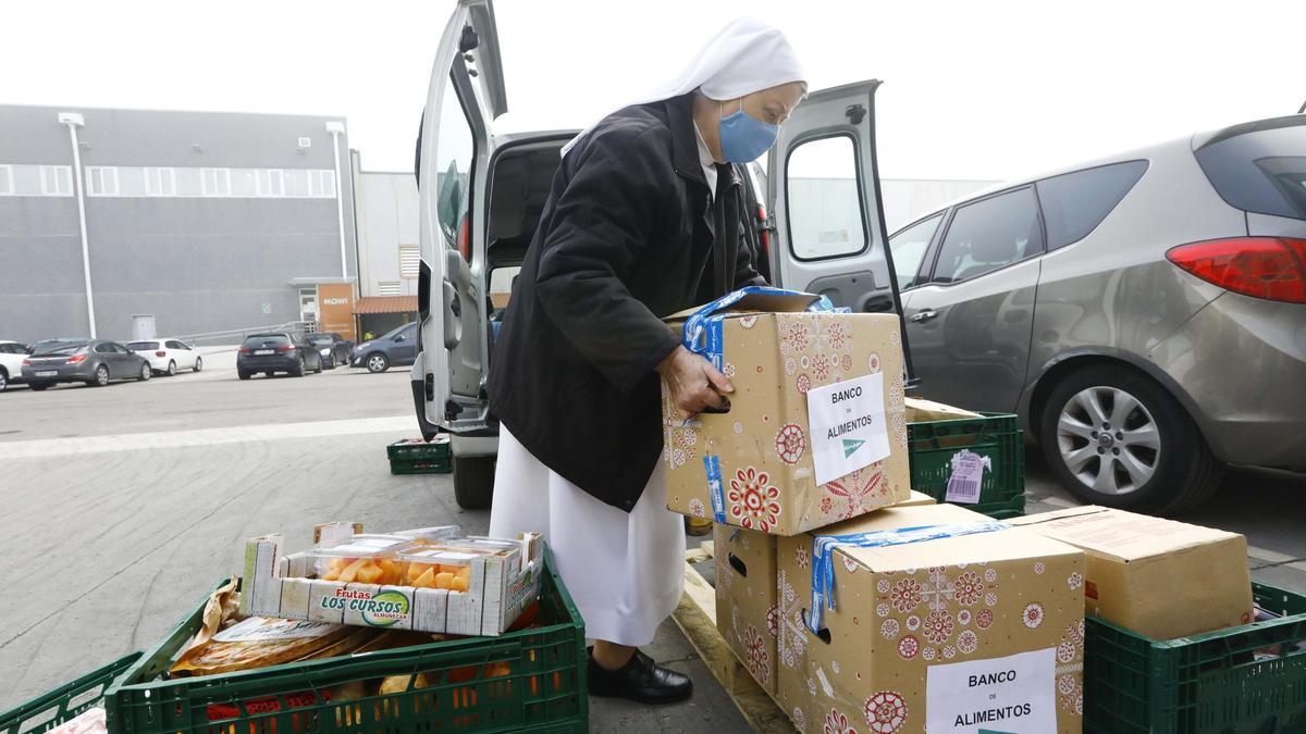 Una religiosa carga lotes de Navidad en una furgoneta, ayer, en la instalación del Banco de Alimentos en Mercazaragoza.