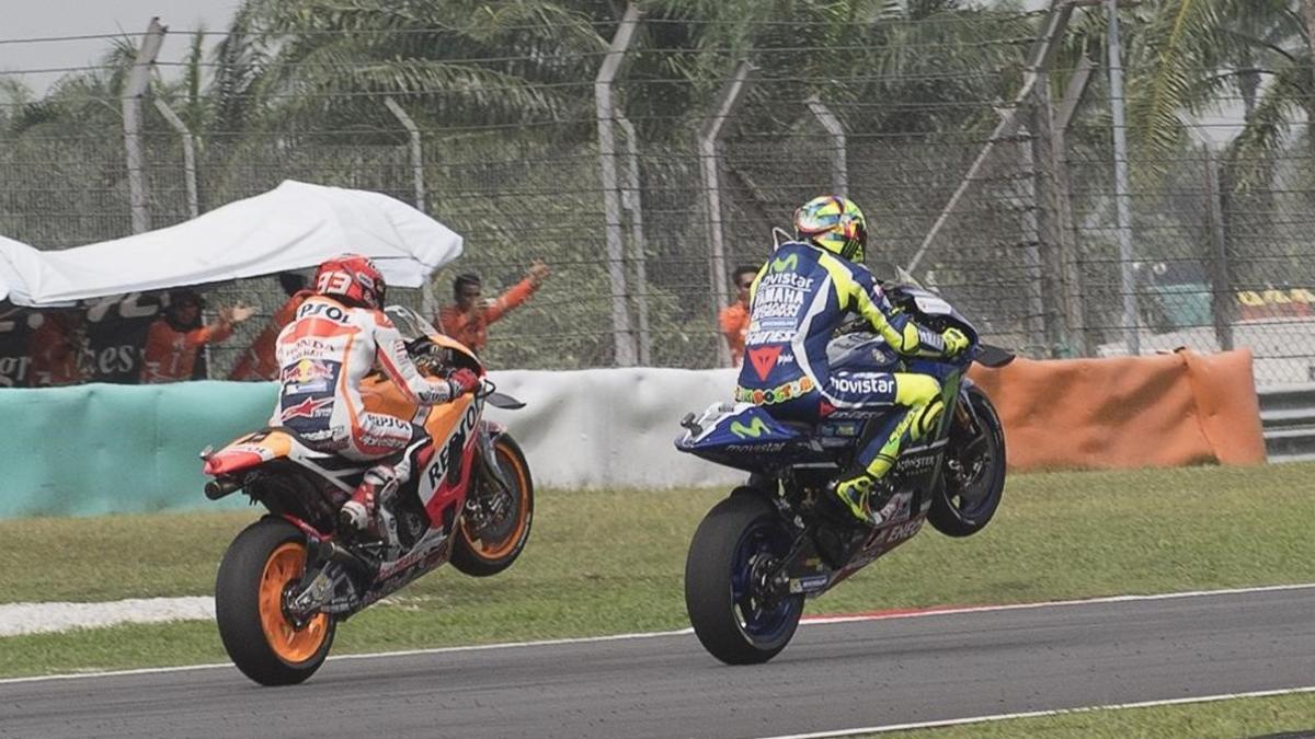 Marc Márquez (Honda) y Valentino Rossi (Yamaha) levantan sus motos en homenaje a Simoncelli, hoy en Sepang.