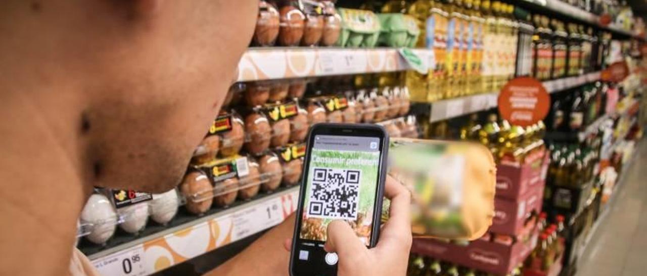 Un comprador consulta en su móvil una app en un supermercado de Alcoy.