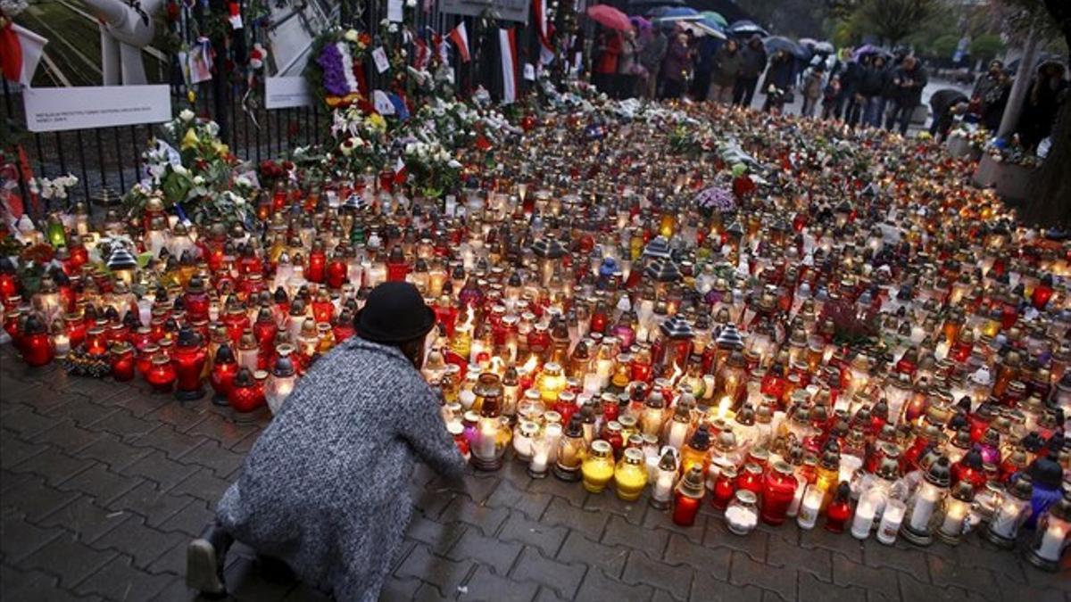 Una muchacha pone velas para conmemorar a las víctimas de los ataques en París frente a la embajada francesa en Varsovia