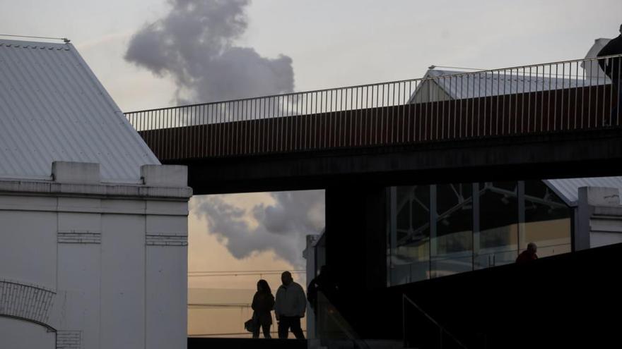 Un penacho de humo industrial con la pasarela que conduce al Niemeyer en primer término.