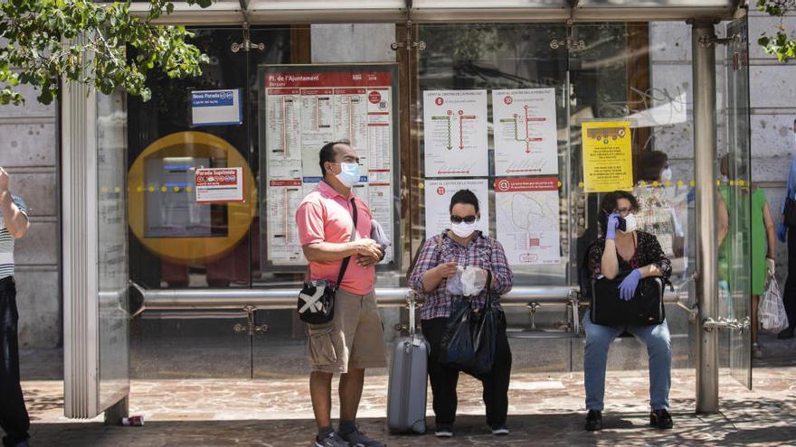 Varias personas esperan el autobús en la Plaza del Ayuntamiento de València.