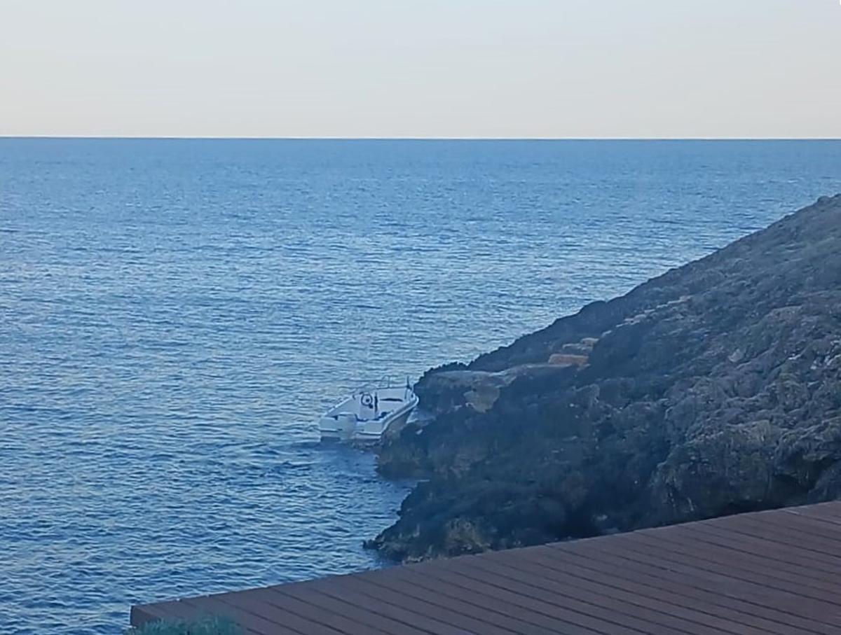 La barca abandonada en las rocas de Cala Olivera.