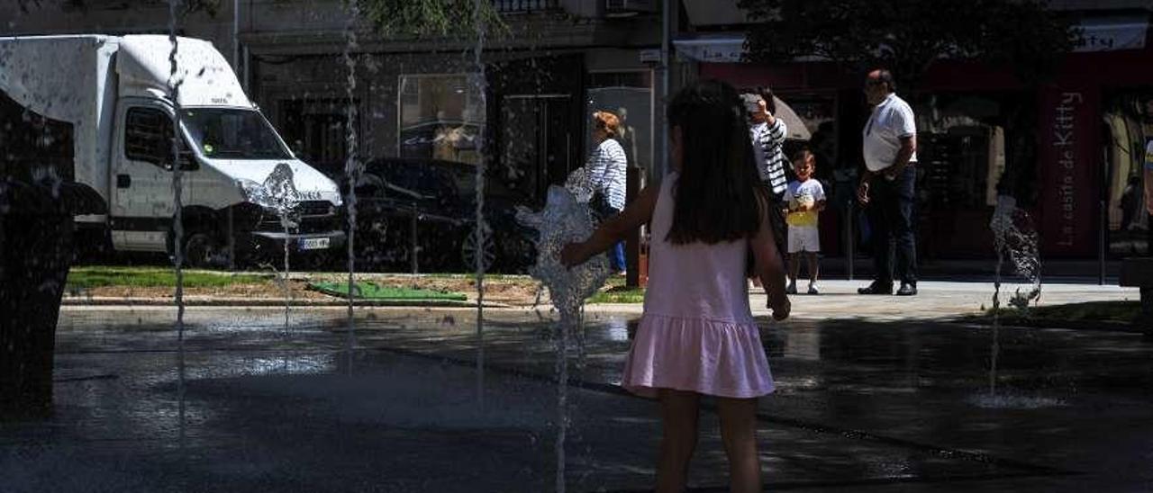 Los niños juegan con los chorros de agua de la Praza da Independencia. // Iñaki Abella