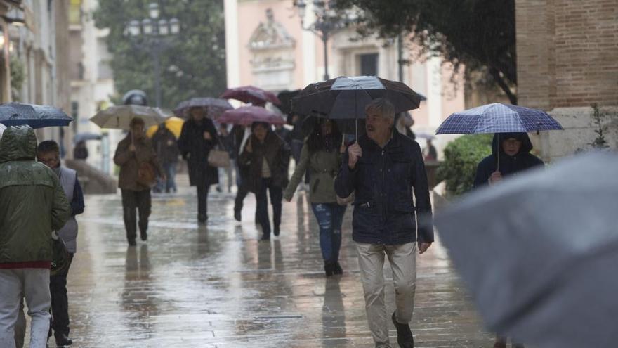 Los viandantes se guarecen de la lluvia bajo sus paraguas.