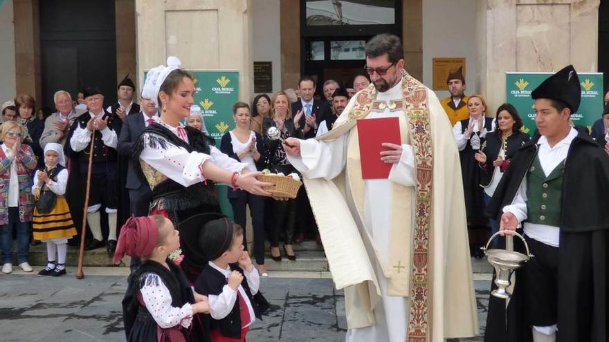 El párroco Juan Hevia bendice la cesta de huevos que sostiene la reina de las fiestas, Marta Bango.