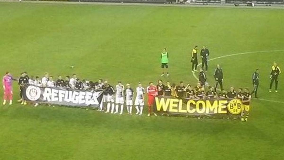 Jugadores del Sankt Pauli y del Dortmund, posando con una pancarta de apoyo a los refugiados