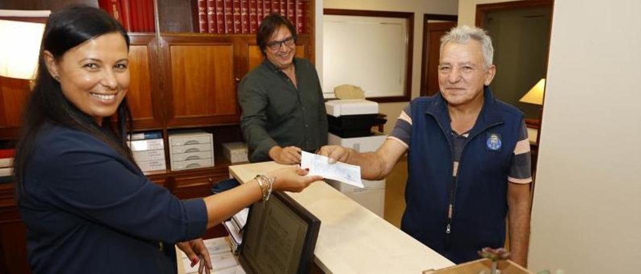 Ramón Barreiro recibió el viernes el cheque de manos de Marta Pérez en el despacho del abogado Tomás Santodomingo (al fondo).