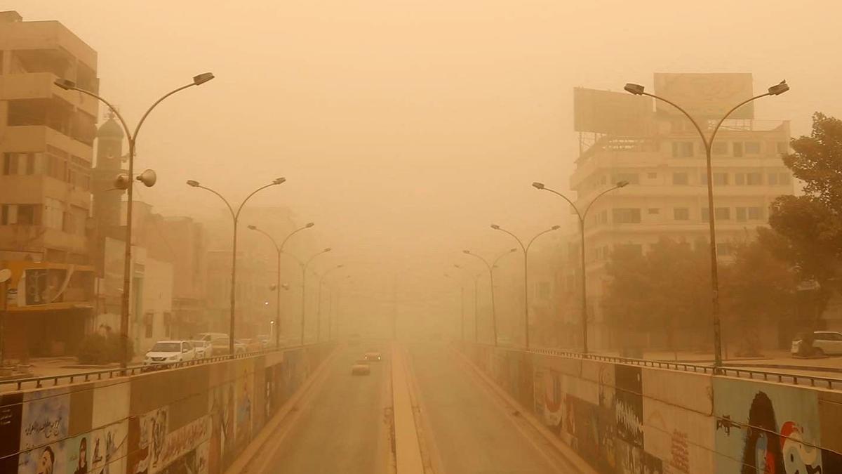 Autos circulan por una calle durante una tormenta de arena en Bagdad, Irak