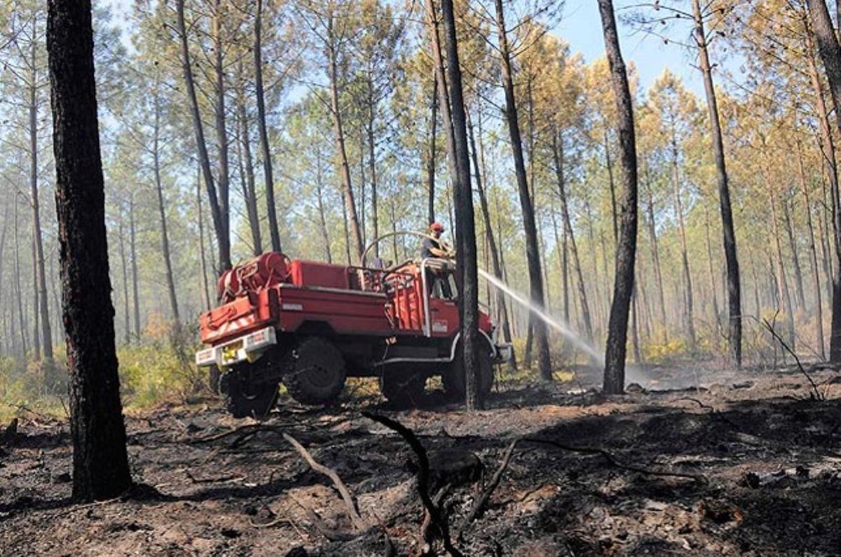 Un camió dels bombers ruixa aigua sobre una àrea boscosa devastada pel foc a prop de Lacanau, França.
