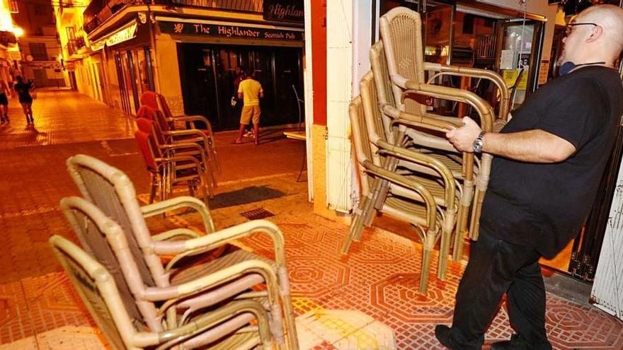 Un trabajador retira la terraza de un bar del West End antes de las 22 horas para cumplir el toque de queda en Ibiza.
