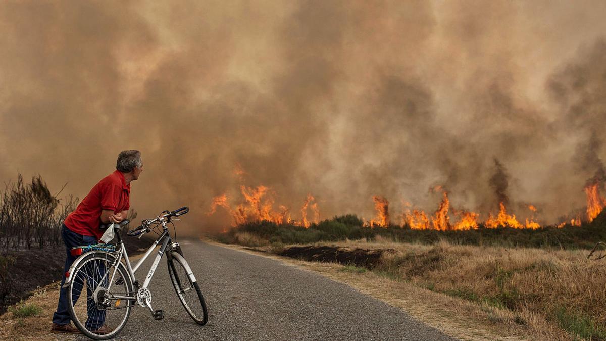 Un vecino  de Cualedro observa el avance de las llamas en un incendio en la localidad.
