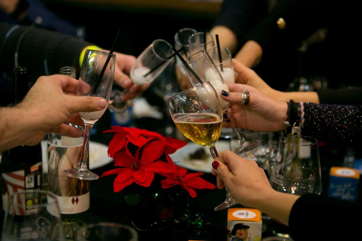 Varias personas brindan en una cena de Nochevieja.