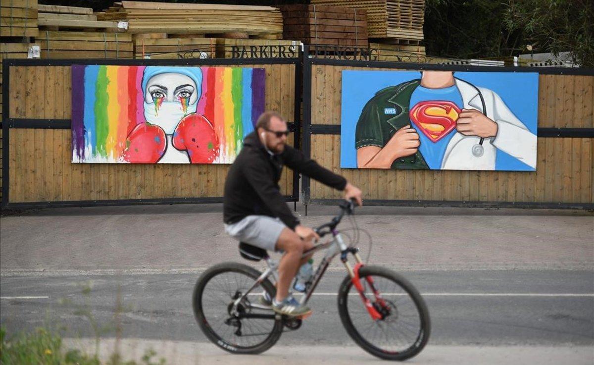 Un ciclista pasa ante un mural de la artista Rachel List en Pontefract, Inglaterra. La obra rinde homenaje al sistema público de salud y su lucha frente al coronavirus.