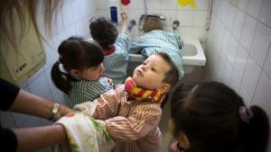 Una profesora ayuda a secarse las manos a sus alumnos de educación infantil antes de ir a comer.