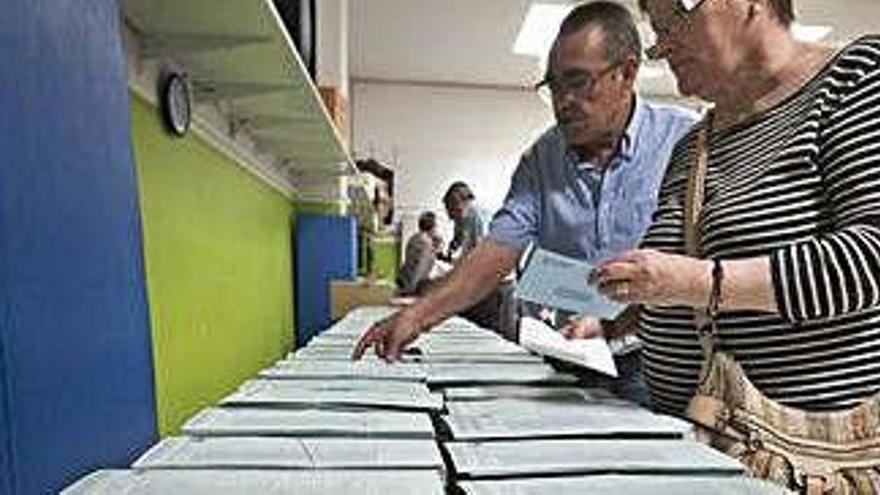 Uns votants examinen les piles de paperetes al col·legi electoral de la Font dels Capellans (Manresa)