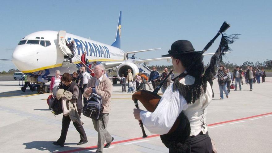 Un gaiteiro recibe en la pista a los pasajeros de un vuelo de Ryanair en el Aeropuerto de Santiago-Rosalía de Castro