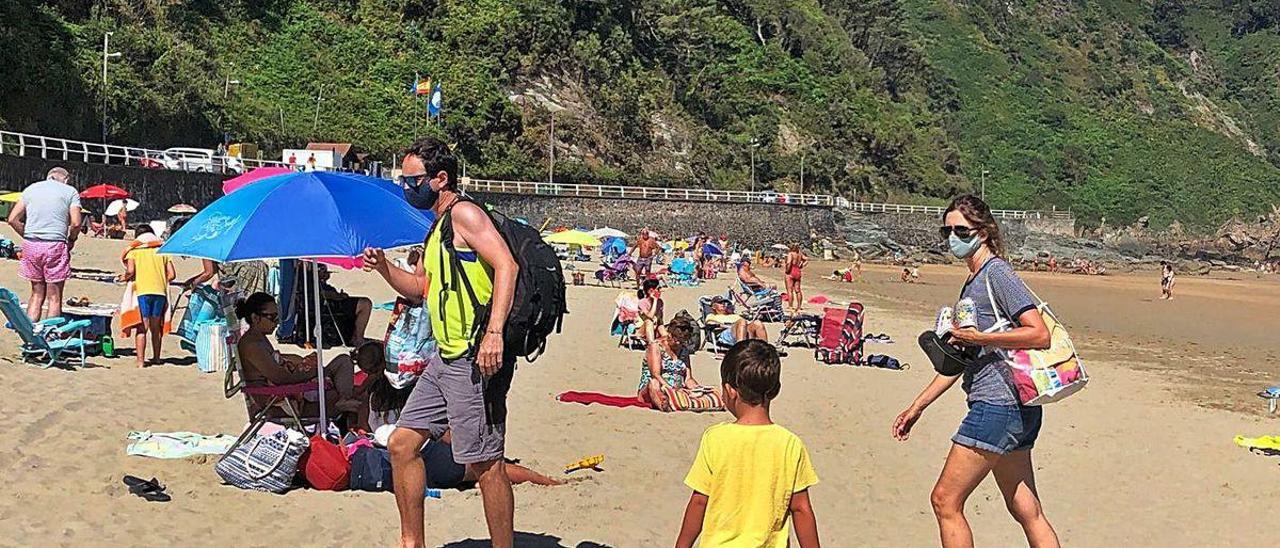 Bañistas caminando con mascarillas en la playa de Aguilar (Muros de Nalón), ayer.