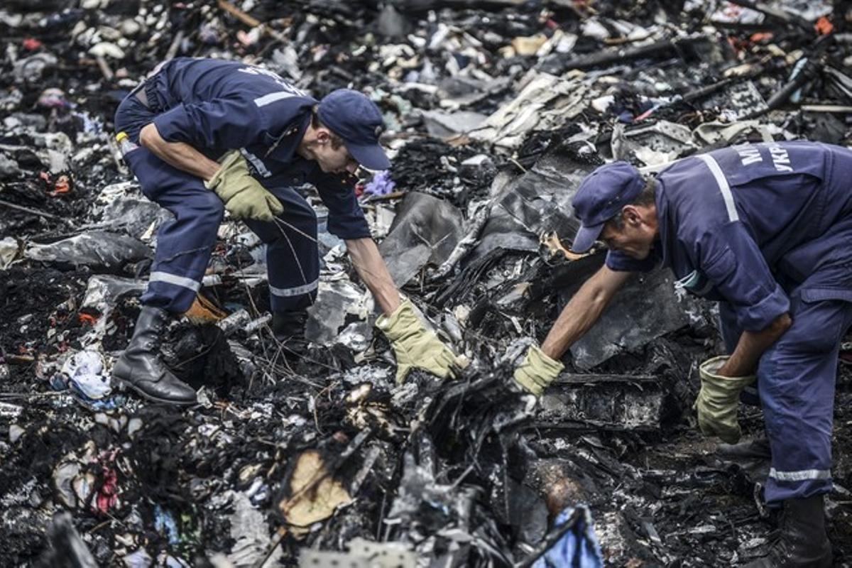Dos agents busquen entre les restes del vol MH17 de Malaysia Airlines, el 20 de juliol a Donetsk (Ucraïna).