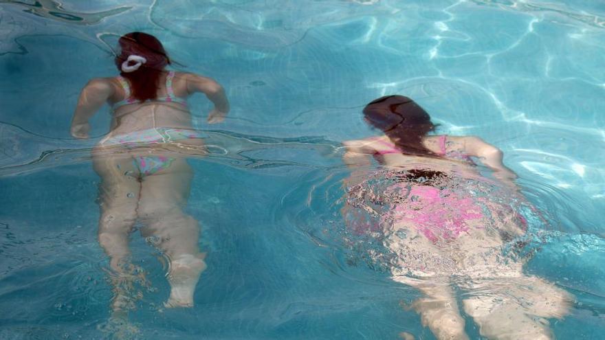 Dos niñas se bañan en una piscina.
