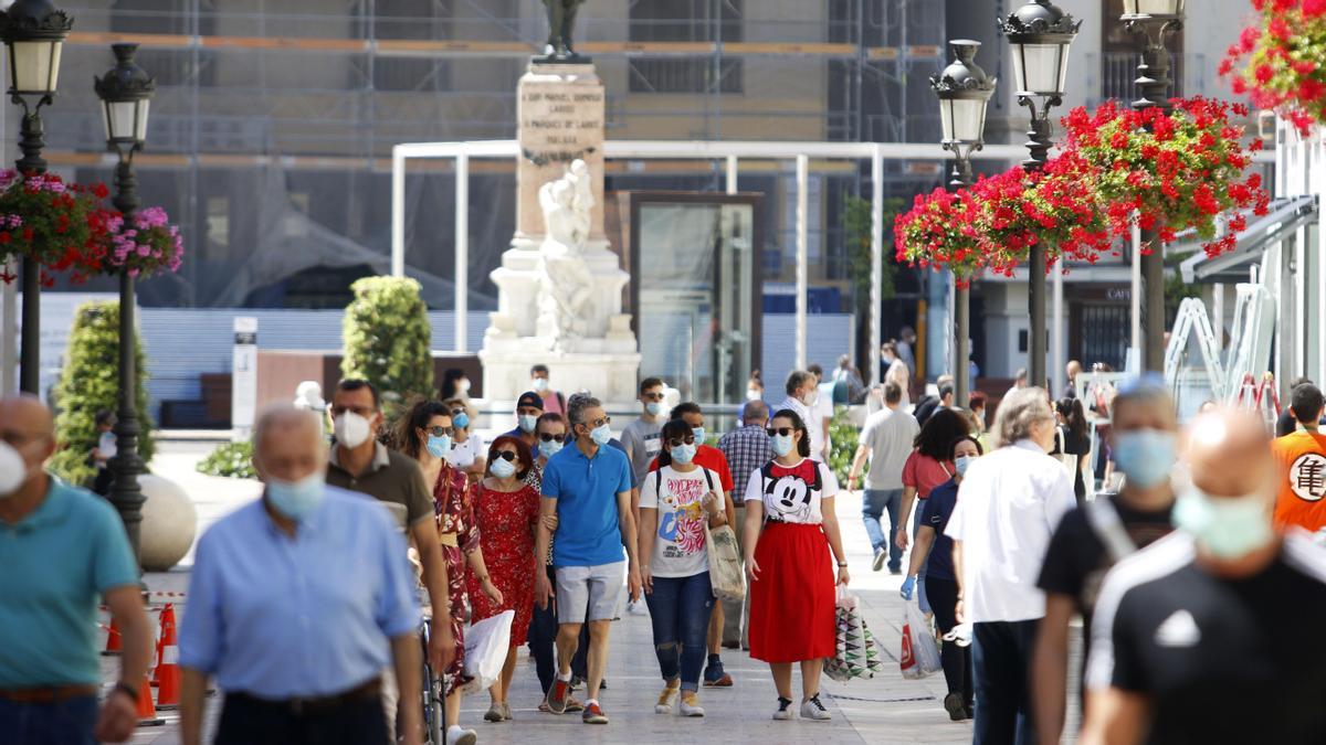 Varias personas pasean por una calle de Málaga con mascarillas.