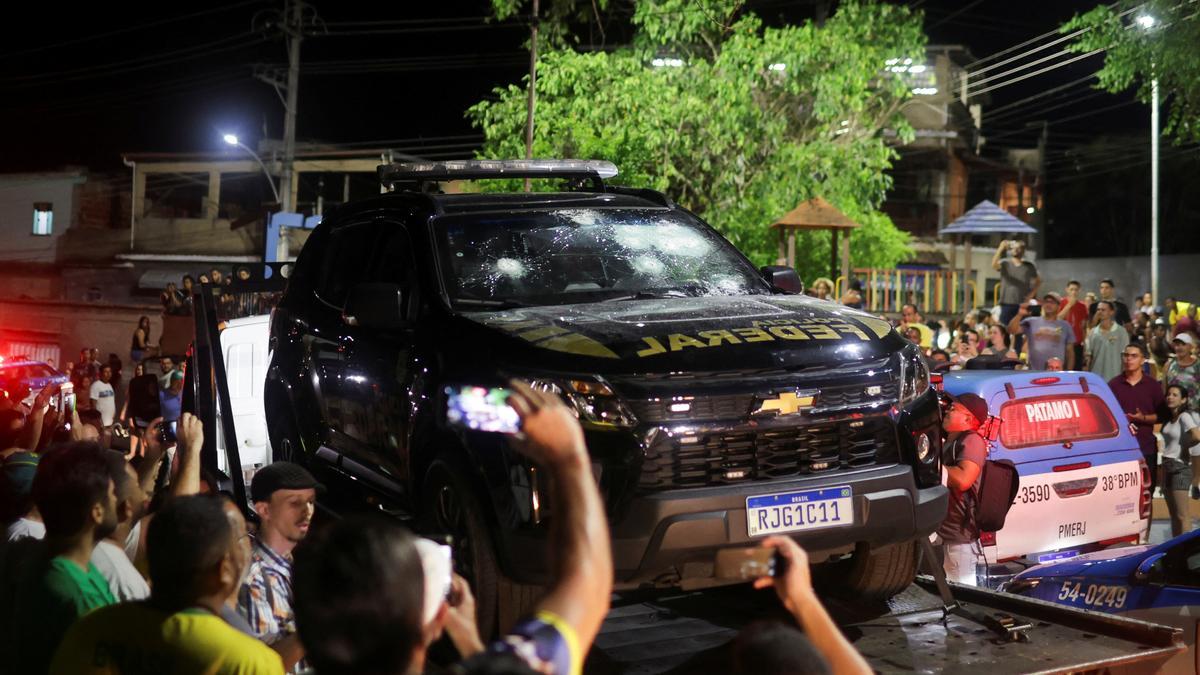 Varias personas toman fotos del vehículo policial dañado por Roberto Jefferson.