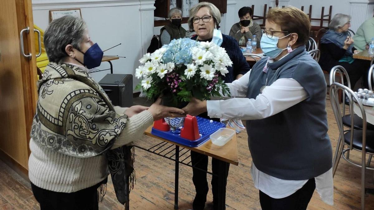 Una socia recibe uno de los centros creados durante el taller de arte floral.