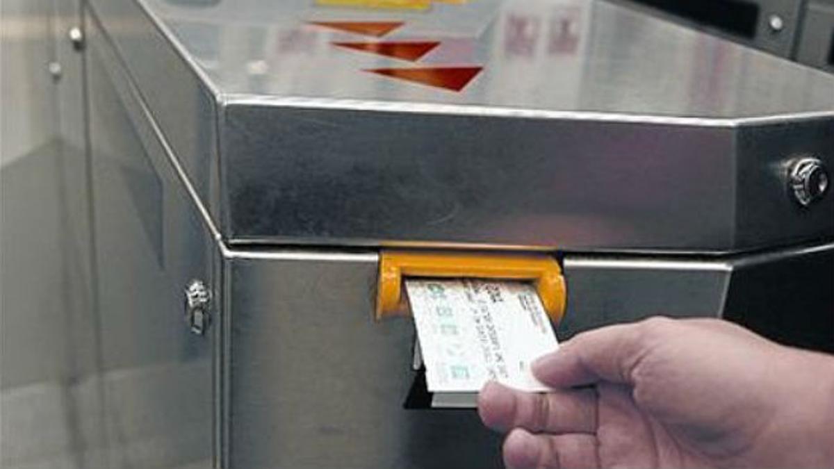 Un pasajero valida una tarjeta de transporte en una taquilla del metro de Barcelona.