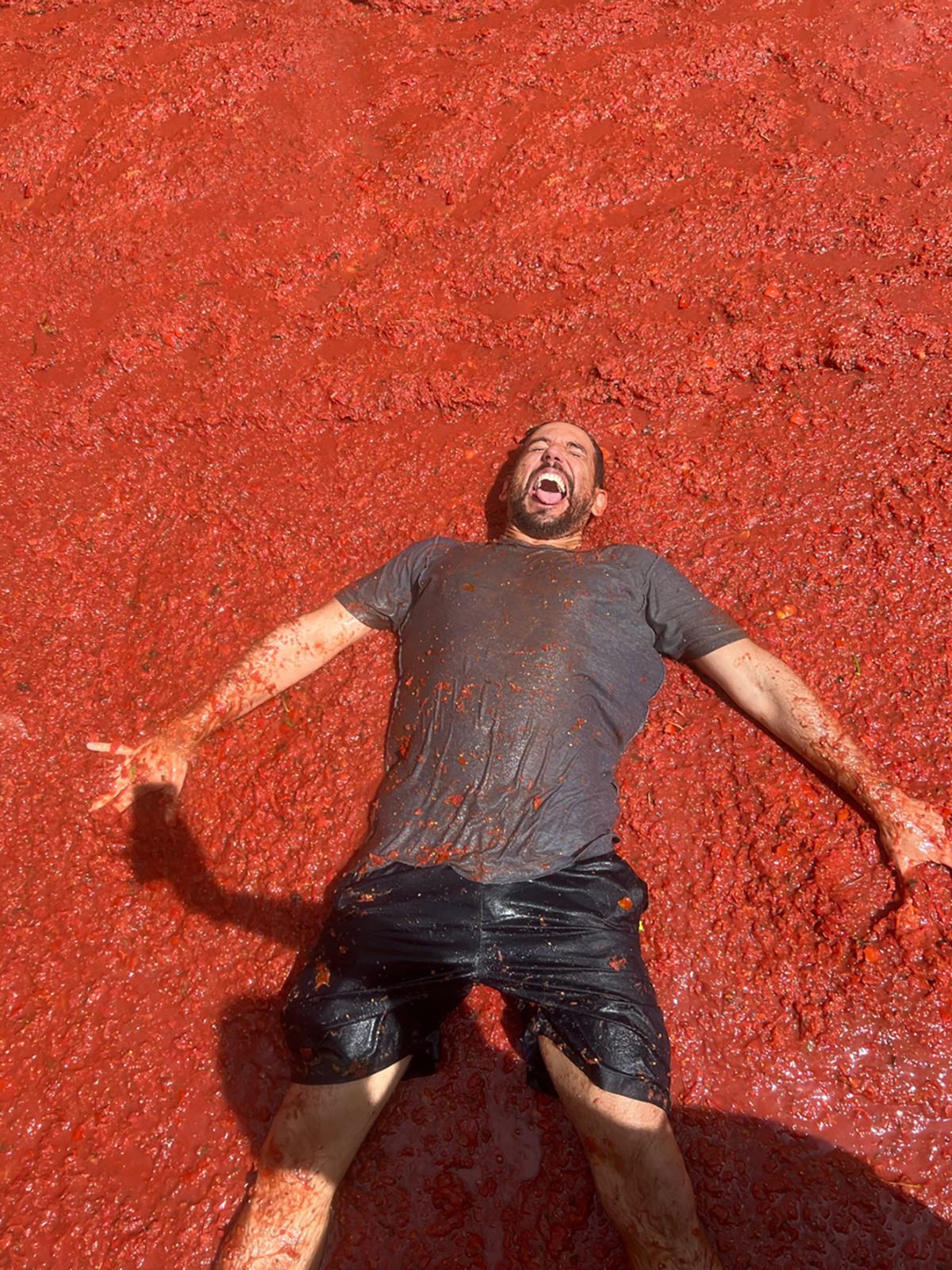 Un participante celebra tumbado sobre un mar de tomate durante La Tomatina, la multitudinaria fiesta que cada agosto tiñe de rojo las calles de Buñol.