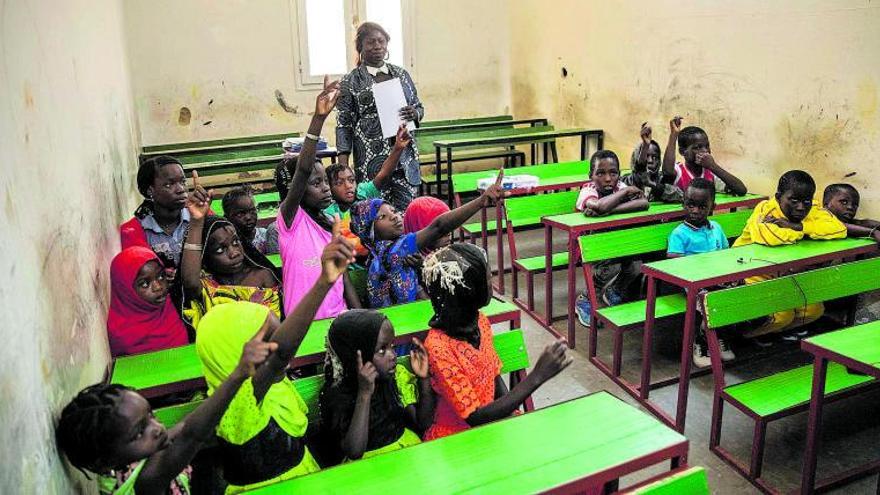 Una maestra y sus alumnos en la pequeña escuela de la Organización de Migrantes de Nuadibú (OMN). | | PABLO BLÁZQUEZ