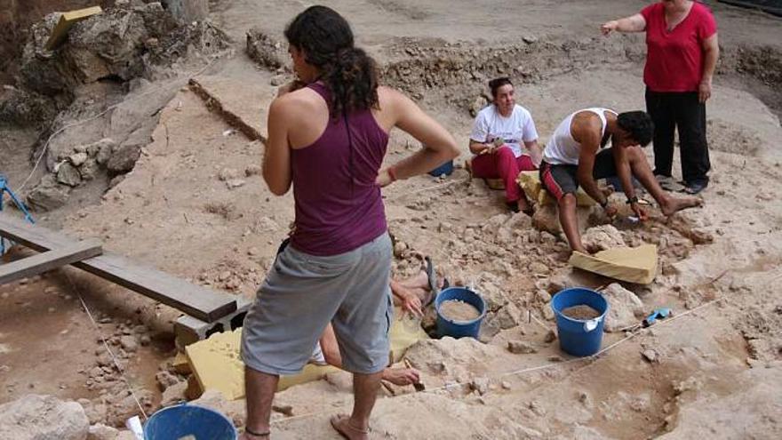 En la imagen superior, el pequeño muro hecho de piedras. En la inferior, detalle del trabajo de los arqueólogos