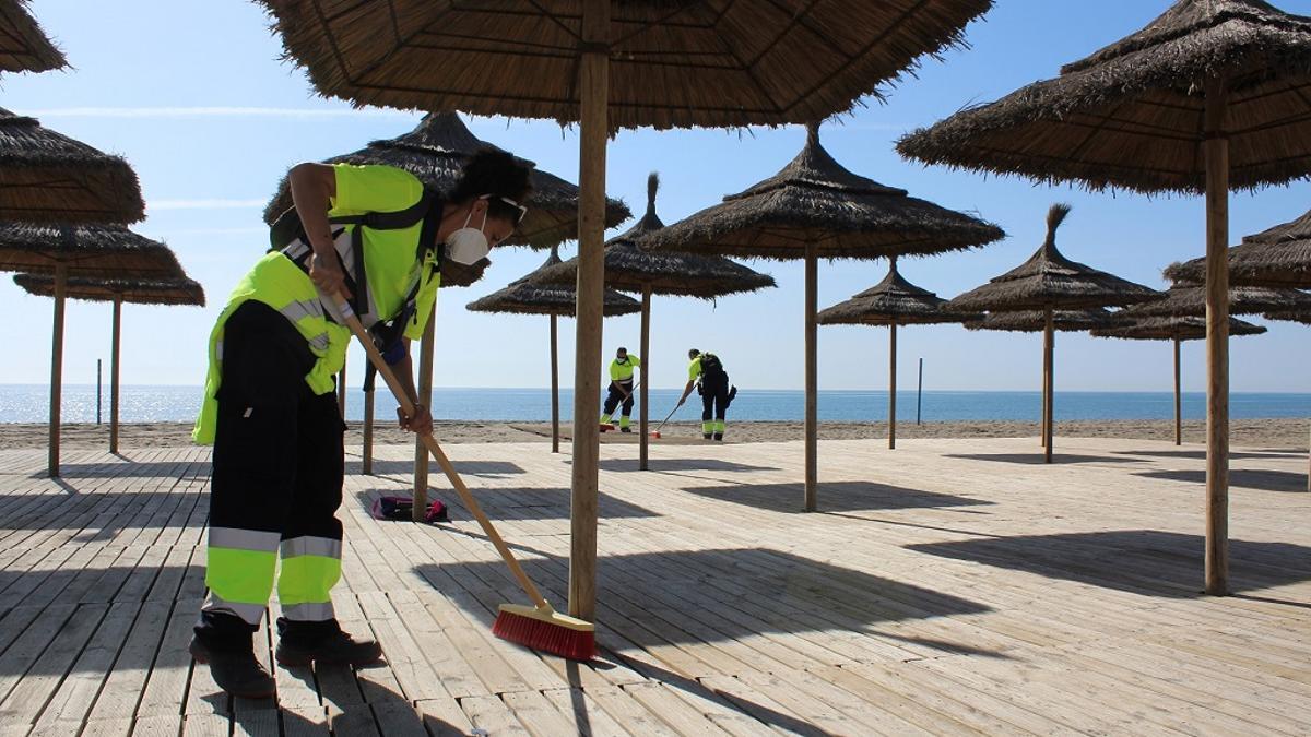 Varios operarios limpian las pasarelas de madera de una playa de Fuengirola.