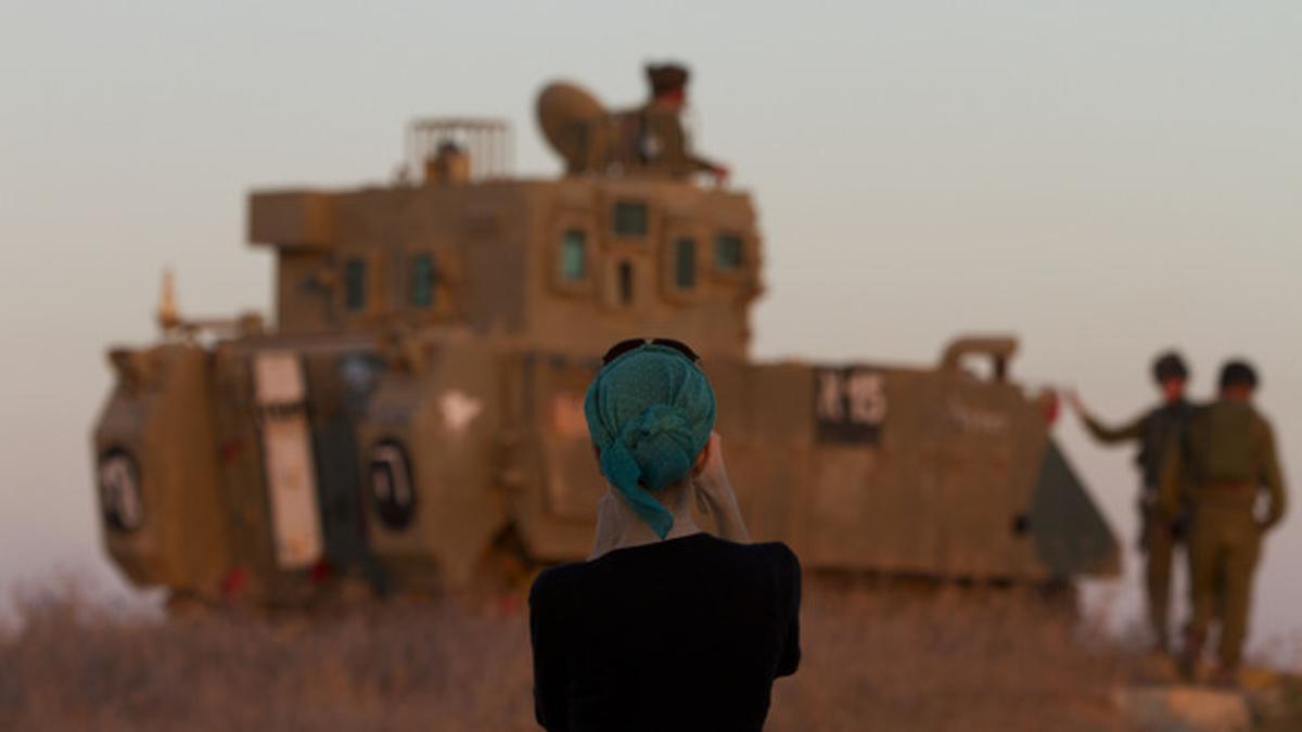 Una mujer fotografía un tanque israelí cerca de la frontera con Gaza