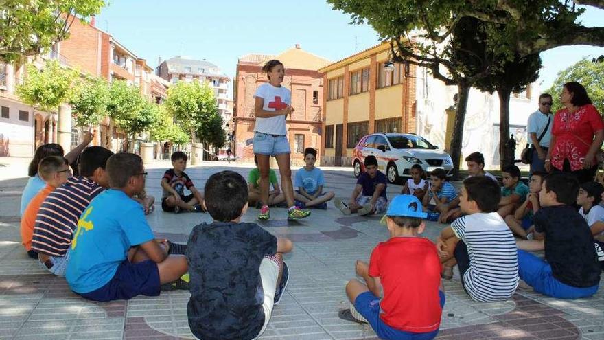 La trabajadora social de Cruz Roja explica a los niños las reglas del juego de cartas.