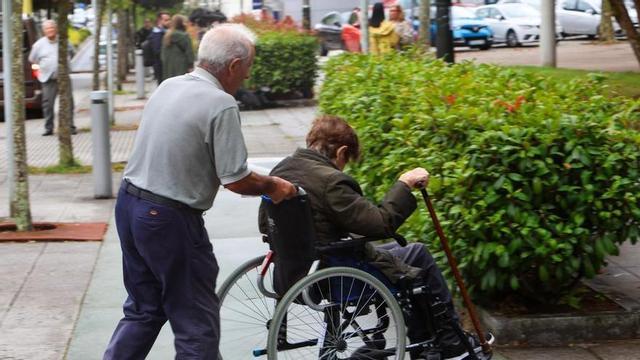 Un home empeny la cadira de rodes d’una dona.