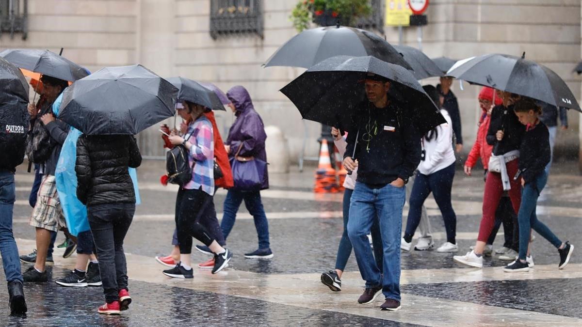 Peatones con paraguas en la plaça de Sant Jaume, hoy martes.