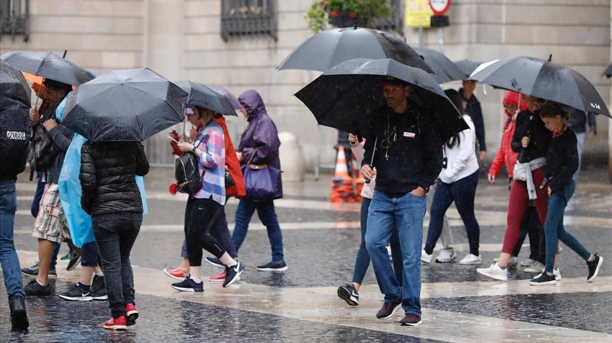 Peatones con paraguas en la plaça de Sant Jaume de Barcelona, en una imagen de archivo.