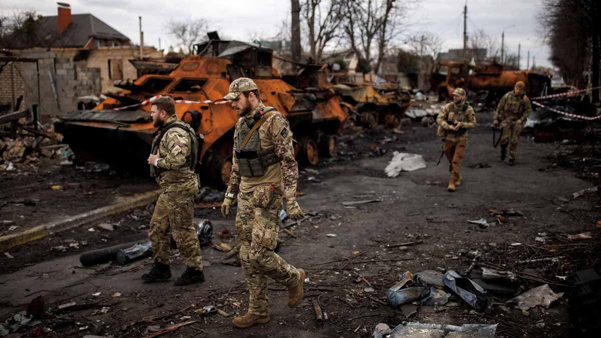 Soldados ucranianos pasan junto a tanques rusos destrozados, en la ciudad de Bucha.