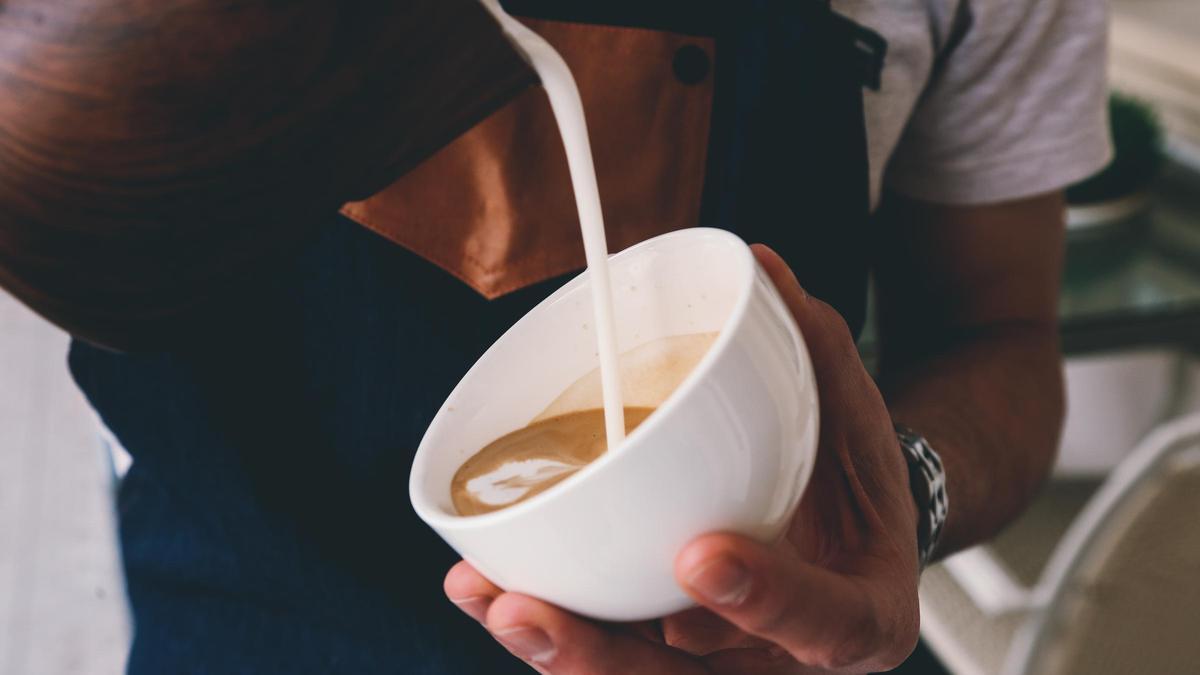 Un barista vierte leche en una taza de café de especialidad.