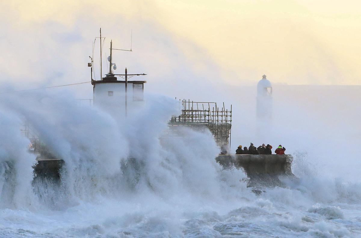  La gente observa cómo las olas chocan contra el malecón en Porthcawl, Gales del Sur